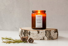 Load image into Gallery viewer, Merry + Bright scented soy wax candle burning brightly in amber jar