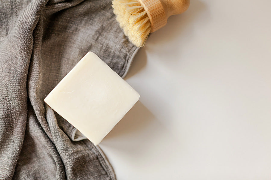 Solid dishwashing soap bar pictured with bamboo sisal dishwashing brush and dish cloth